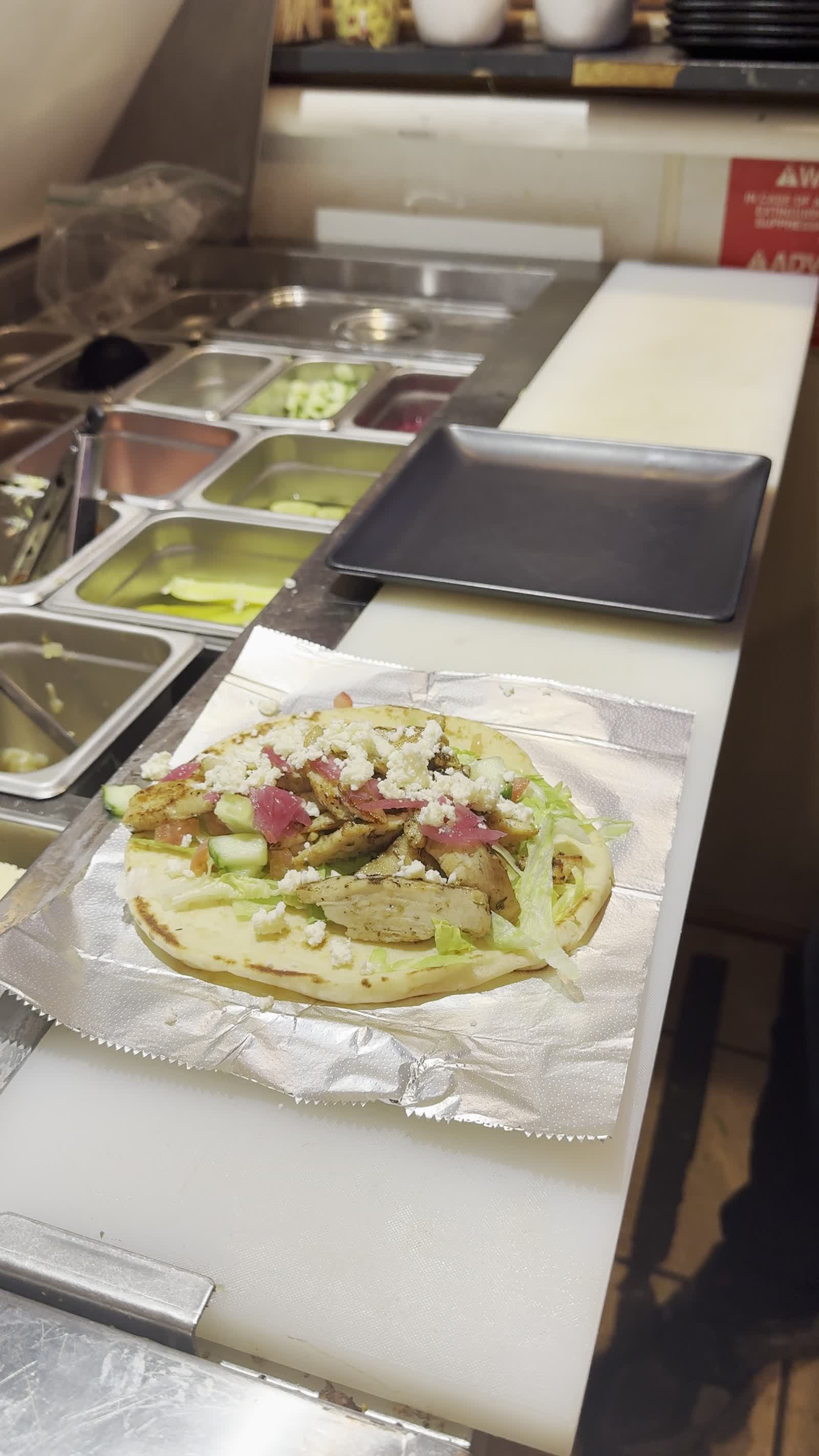 Chicken donor kebab wrap with feta, cucumber, pickled red onion, and tzatziki on naan