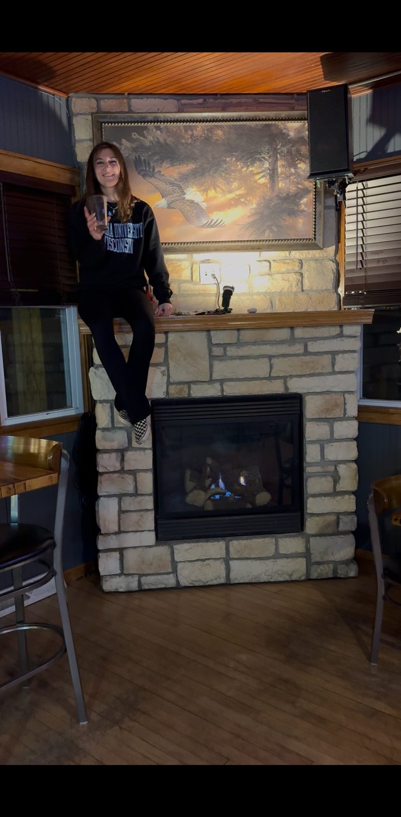 By the stone fireplace with a drink